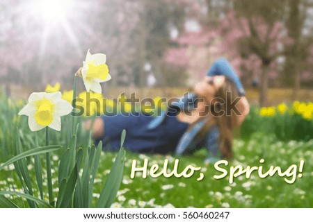Hello, Spring! text on a blurry picture with a beautiful girl, yellow daffodils, flowering cherry tree, sunlight. 