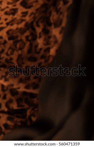 Leopard skin texture. Dark silk background.