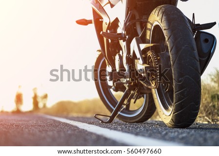 A motorcycle parking on the road right side and sunset, select focusing background. Royalty-Free Stock Photo #560497660