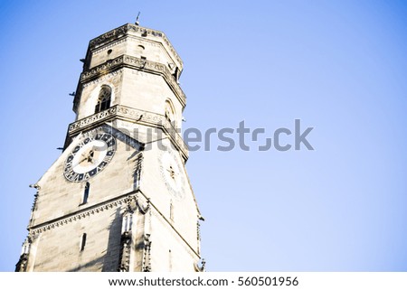 Old church bell tower with clock face with blue sky background
