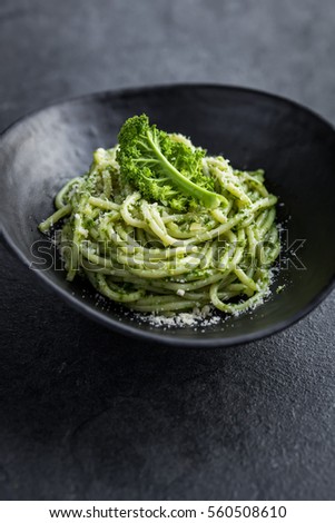 spaghetti pasta with  kale pesto sauce and parmesan cheese in black bowl, dark background, selective focus