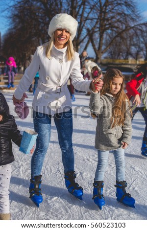Mother and daughter enjoy in skating ring.Colored photo