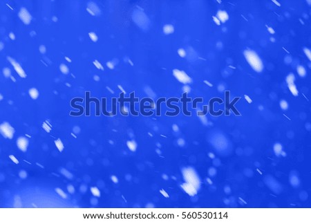 Falling snow on blue background, motion blur