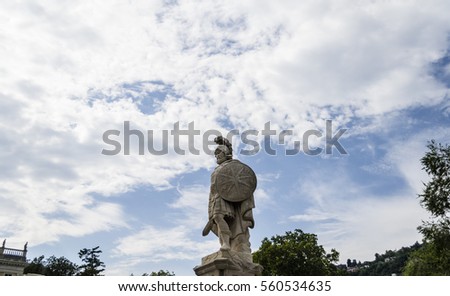 a statue of a Roman gladiator with an interesting sky in the background