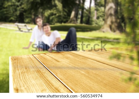 Wooden table of free space for your decoration and two young lovers on green grass and valentine`s day time 