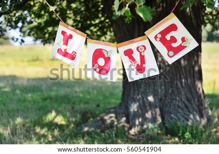 the word love from red letters hanging on the big tree in the summer