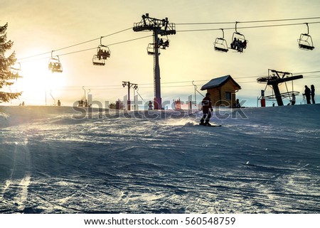 skier on ski slope - ski chair lift late afternoon Royalty-Free Stock Photo #560548759