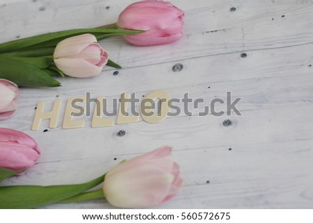 spring hello background with tulips on wooden background. rustic hello wooden word