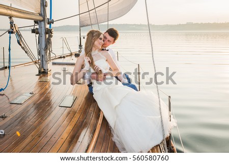 Happy bride and groom hugging on a yacht - looking into each other
evening yellow sun