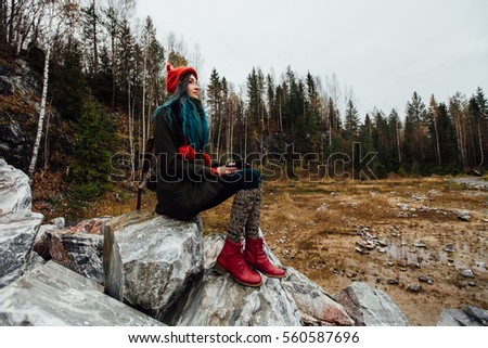 artist girl painting sitting on the rocks at the cliff, notepad. Wonderful autumnal view
