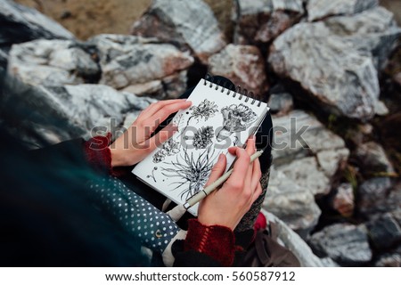 artist girl painting sitting on the rocks at the cliff, notepad. Wonderful autumnal view