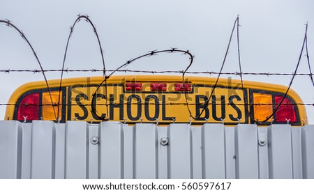 School bus parked behind barbed wire fence