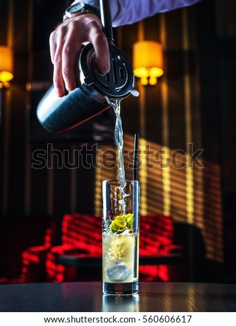 Barman at work, preparing cocktails. pouring Mai tai to cocktail glass. concept about service and beverages. Royalty-Free Stock Photo #560606617