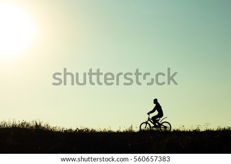 Silhouette of a female cyclist riding Movement on the background of a beautiful sunset.