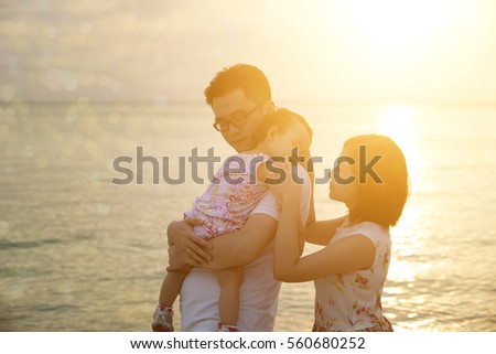 Silhouette of Asian family outdoor fun, enjoying holiday together on seaside in sunset during vacations.