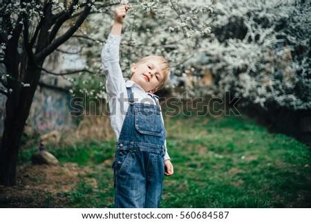 Portrait of little blonde boy playing in spring garden looking at camera