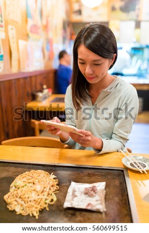 Woman taking photo on Okonomiyaki in Japanese restaurant