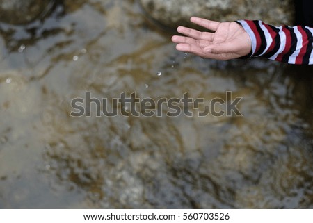 A travel image of a girl playing with water in river with her hand