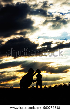 Mother and son with silhouette at sunset.