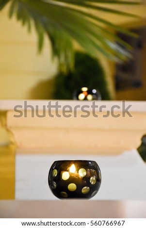 Candles on a restaurant terrace with a palm leaf in the background