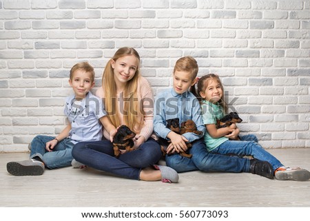 Cute children with little dog laying on the floor on brick wall background. Kids Pet Friendship.