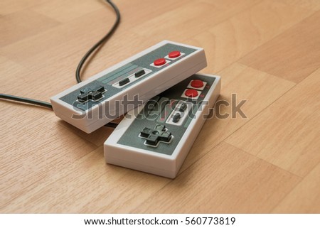 Retro NES console controller with black and red buttons on a wooden table