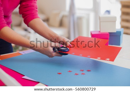 Young woman make scrapbook of the papers on the table using tools for cutting paper. Hand made photo album.Shallow depth of field