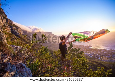 Man holding a south african flag over Cape Town Royalty-Free Stock Photo #560808874