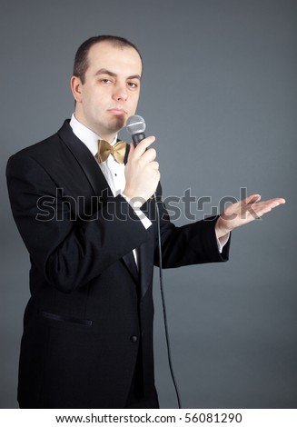 Man in tuxedo talks into microphone