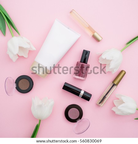 Flat lay, top view table desk frame. Feminine desk workspace with cosmetics, lipstick and flowers on background.