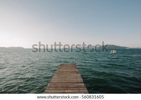 a wooden jetty facing sea with a boat and islands in front of it taken in Tanjung Aru, Sabah, Malaysia in 2016.