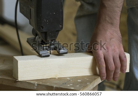 Man cutting wood block with fretsaw at the workshop, close-up, real life   Royalty-Free Stock Photo #560866057
