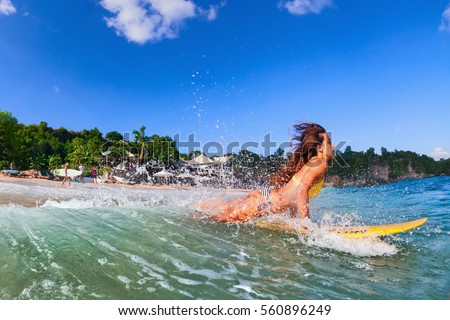 Girl in bikini has fun on surf board - woman surfer run into water, jump with splashes through ocean wave. People in water sport adventure camp, beach extreme activity on summer beach family vacation