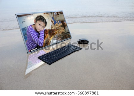 Computer on the beach with Asian girl and sea turtles on the screen,Marine conservation concept
