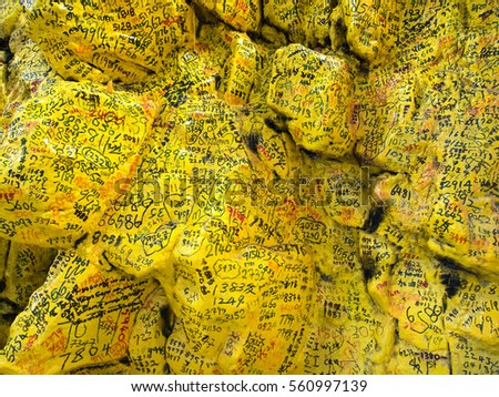 Well wishes prayers lottery numbers scribbled by devotees worship outdoor altar rich on yellow painted stones rocks jungle forest on South East Asia country Kusu island Singapore