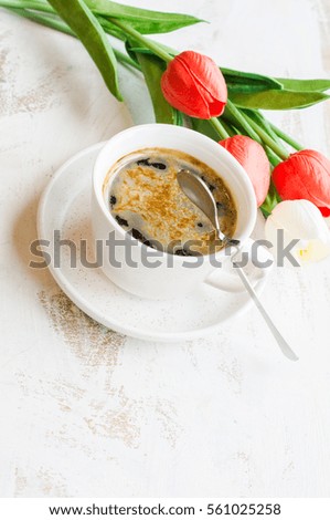 Cup of coffee and spring tulip flowers on white wooden rustic table with copyspace