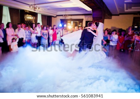 Amazing first wedding dance of wedding couple with heavy smoke and different lights. Blured bokeh effect.