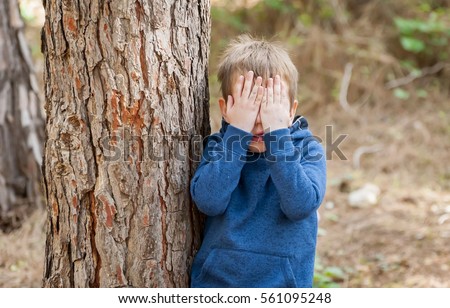 Little Caucasian boy closing his face with hands as if playing hide and seek or scared of something. Hiding face. Closed face. Autism, autistic child, aspergers, asperger's disorder, autistic boy Royalty-Free Stock Photo #561095248