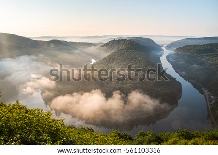 Foggy morning at Saarschleife river loop in Saarland, Germany Royalty-Free Stock Photo #561103336