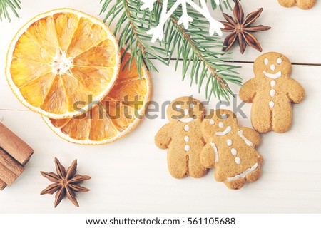 men gingerbread and dried oranges with Christmas tree branches on wooden background - top view