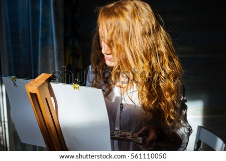 Attractive woman painting with watercolor at the easel