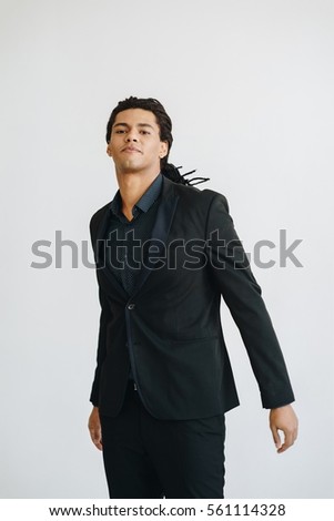 Young businessman in black suit and blue shirt standing over white background. 