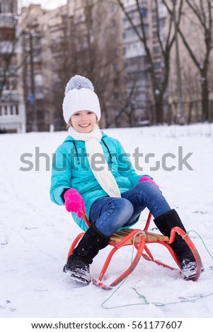 Happy teenage girl having fun on her sled in winter. Winter portrait of teenage girl. Seasonal outdoor activities.