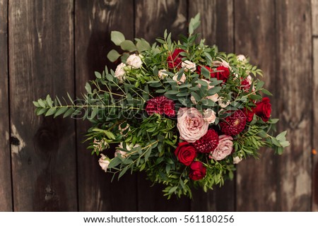 Wedding flower composition with red peony and roses on wood background 