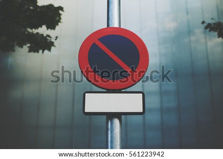 "No parking" road sign with blank frame for your text placed on street lantern, blurred tiled facade of building behind