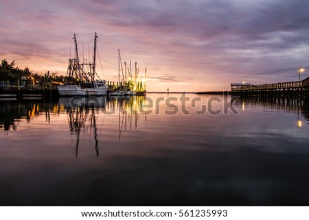 Sunset over Shem Creek in Mount Pleasant, South Carolina with the fishing boats in the distance.  Royalty-Free Stock Photo #561235993