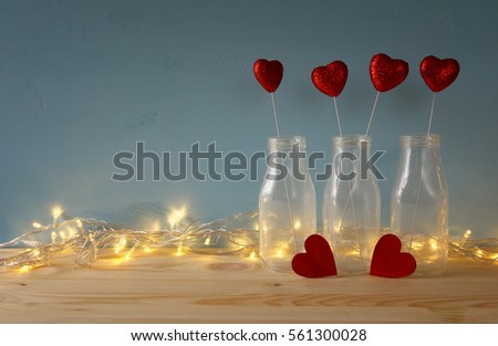 Valentines day background. Glitter hearts in the glass vases on wooden table