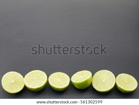 Fresh ripe sliced limes on the black leather background. Top view with copy space.