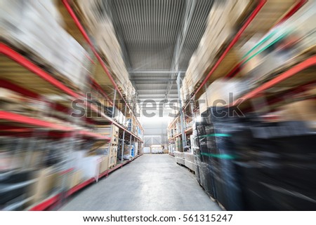 Warehouse industrial and logistics companies. Many boxes packed in a black stretch film. The boxes on high shelves stocked. The effect of motion blur.