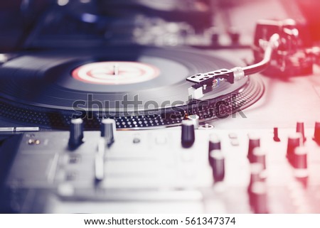 Dj turntable vinyl record player.Professional disc jockey equipment for playing music in the club.High quality sound system.Red light leak effect.Focus on turn tables needle cartridge Royalty-Free Stock Photo #561347374